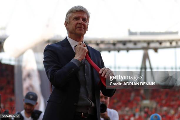 Arsenal's French manager Arsene Wenger starts to take off his tie whcih he hands to a boy in the crowd after the English Premier League football...