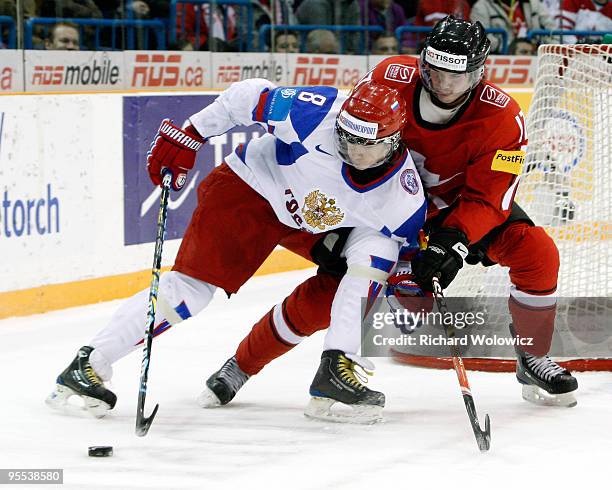 Alexander Burmistrov of Team Russia stick handles the puck while being defended by Tim Weber of Team Switzerland during the 2010 IIHF World Junior...