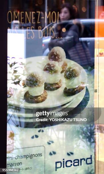 Pedestrian is reflected on a show window of French food giant Picard's first shop in Tokyo at a press preview on November 21, 2016. Picard and...