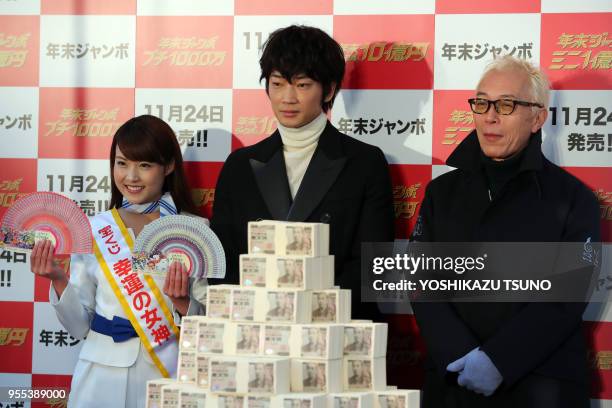 Japanese actors Go Ayano and Geoge Tokoro display one billion yen in cash for the "Year-end Jumbo Lottery" as the first tickets go on sale in Tokyo...