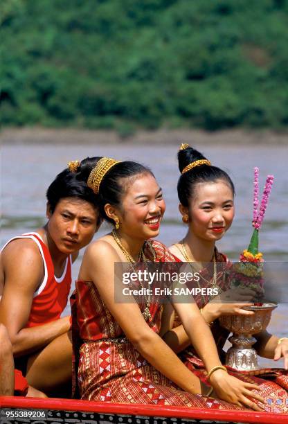 Deux jeunes filles dont une tient un trophée aux couleurs de son équipe durant la fête des pirogues, circa 2000, en bordure du Mekong, Laos.