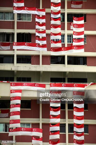 Drapeaux nationaux de Singapour pendus au balcon des immeubles de la ville-etat en preparation des commemorations du 9 aout 2015 pour celebrer le...