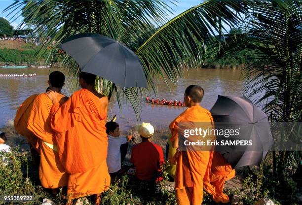 Des moines parmi les spectateurs obsevent la course durant la fête des pirogues, circa 2000, en bordure du Mekong, Laos.