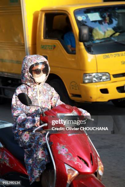 Pour se proteger des effets de la canicule dépassant les 40 degres Celsius dans la capitale Vietnamienne, les conducteurs de scooters se recouvrent...