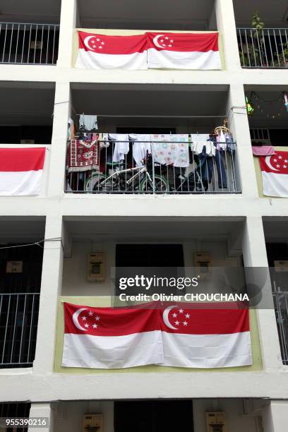Drapeaux nationaux de Singapour pendus au balcon des immeubles de la ville-etat en preparation des commemorations du 9 aout 2015 pour celebrer le...