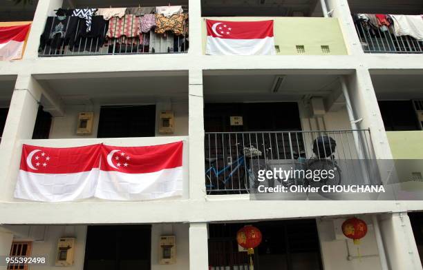 Drapeaux nationaux de Singapour pendus au balcon des immeubles de la ville-etat en preparation des commemorations du 9 aout 2015 pour celebrer le...