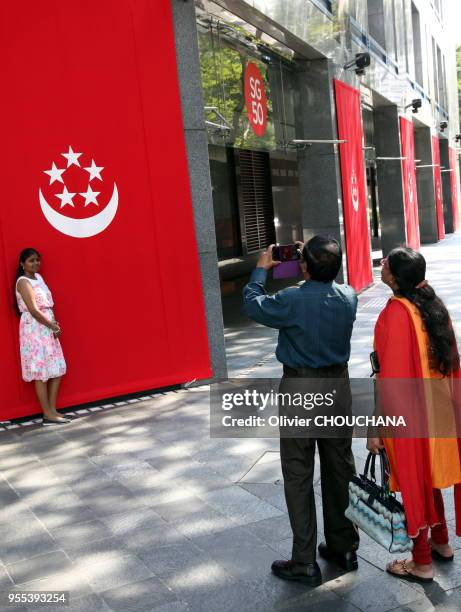 Des singapouriens se prennent en photos devant les décorations de la ville-etat en preparation des commemorations du 9 aout 2015 pour celebrer le...