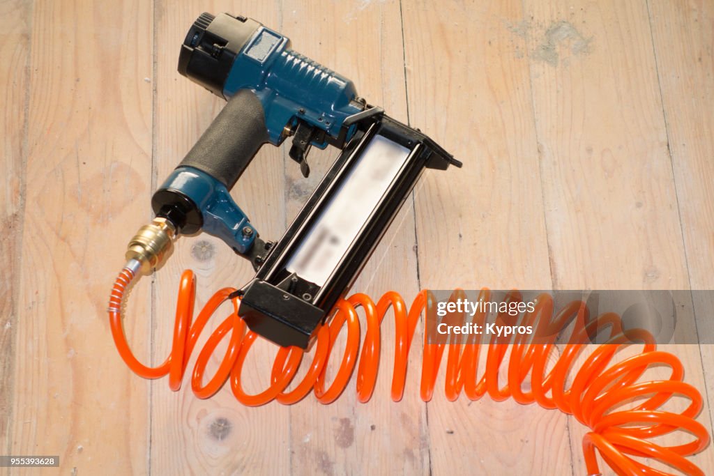 Europe, Greece, 2018: View Of Compressed Air Tool - 50mm Air Brad Nailer Attached To Spiral Compressor Hose