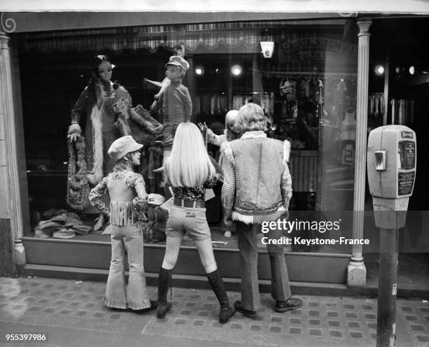 Devant une vitrine d'un magasin d'habillement sur Carnaby Street, trois enfants regardent les vêtements, à Londres, Royaume-Uni.