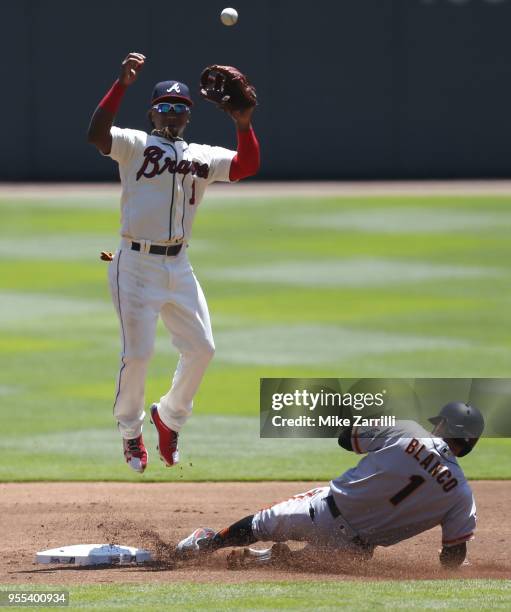 Second baseman Ozzie Albies of the Atlanta Braves jumps for a throw while left fielder Gregor Blanco of the San Francisco Giants slides into second...