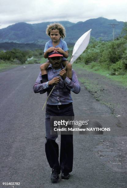 Un homme avec un drapeau blanc improvisé fuit les combats un enfant perché sur ses épaules pendant la guerre civile en juin 1979 au Nicaragua.