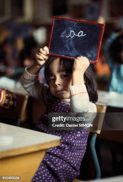 Elève de primaire apprenant à écrire avec une ardoise circa 1980 en France.