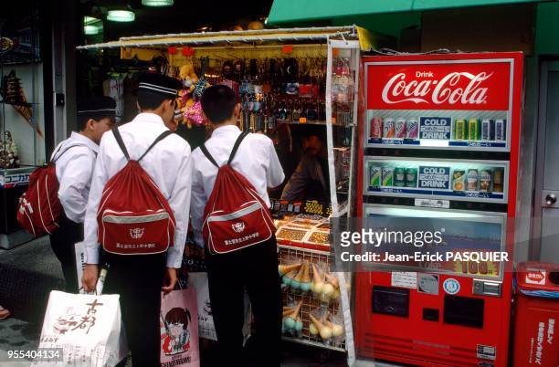 Kyoto, jeunes japonais achetant des souvenirs à un marchand ambulant, à côté d'un distributeur de Coca-Cola. Japon: Kyoto, jeunes japonais achetant...