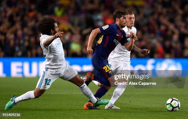Sergi Roberto of Barcelona evades Toni Kroos and Marcelo of Real Madrid during the La Liga match between Barcelona and Real Madrid at Camp Nou on May...