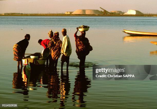 Groupe de personnes autour d'une barque, circa 1990, port fluvial de Kaolack sur le fleuve Saloum, Sénégal.