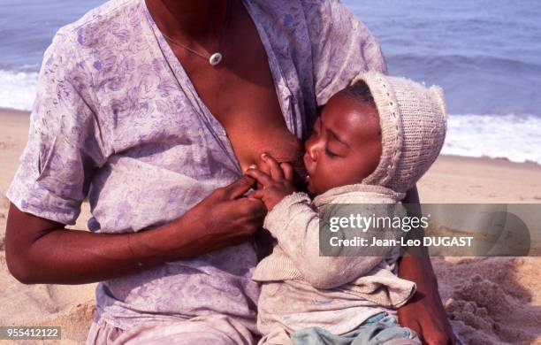 Femme allaitant son bébé sur la plage de Saint-Augustin, Madagascar.