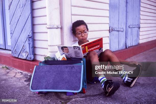 Enfant lisant une bande dessinée à la sortie de l'école à Cayenne, Guyane française.