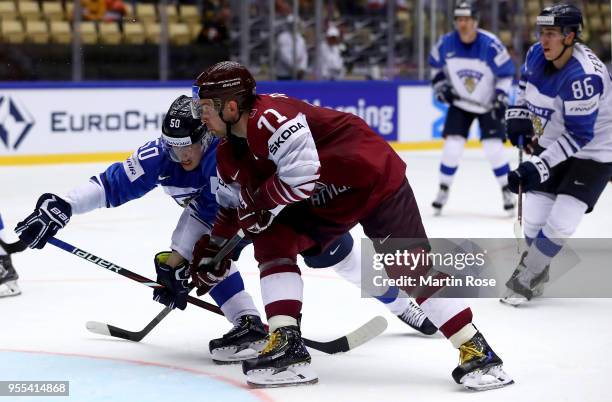 Roberts Bukarts of Latvia and Juuso Riikola of Finland battle for the puck during the 2018 IIHF Ice Hockey World Championship group stage game...