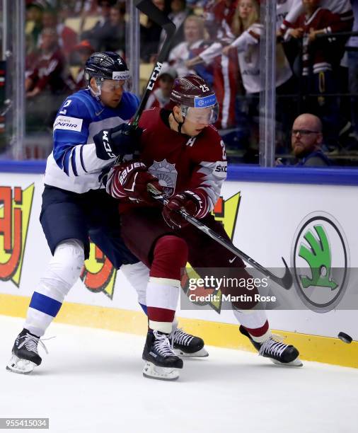 Andris Dzerins of Latvia and Ville Pokka of Finland battle for the puck during the 2018 IIHF Ice Hockey World Championship group stage game between...