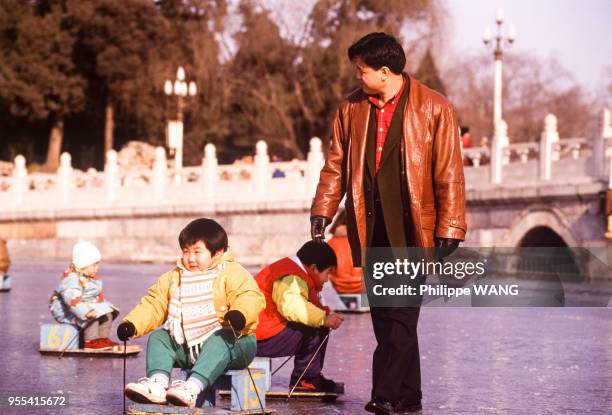 Enfants faisant de la luge sur le lac gelé du parc Beihai à Pékin, Chine.