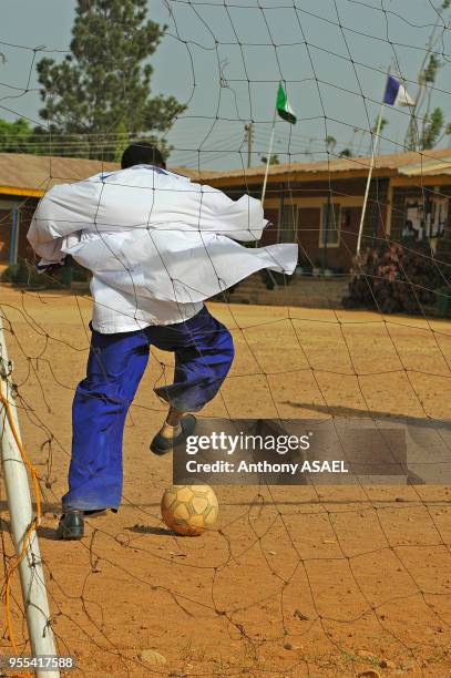 Jeune garçon jouant au foot dans la cour de récréation, Jos, Nigéria.