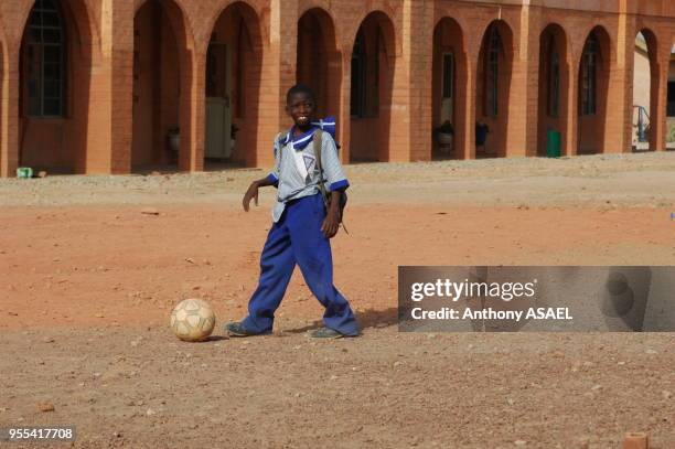 Jeune garçon jouant au foot dans la cour de récréation, Jos, Nigéria.