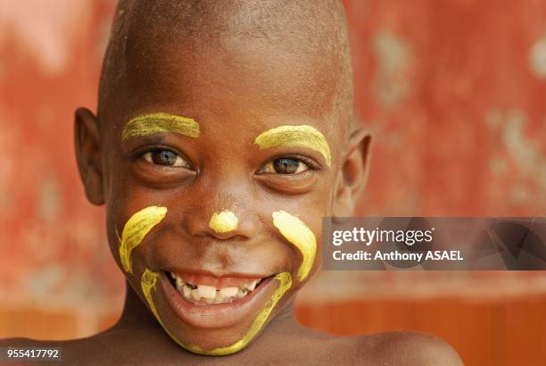 Colombian boy with face paint and shaved head and big toothy smile, Tierrabomba, Colombia.