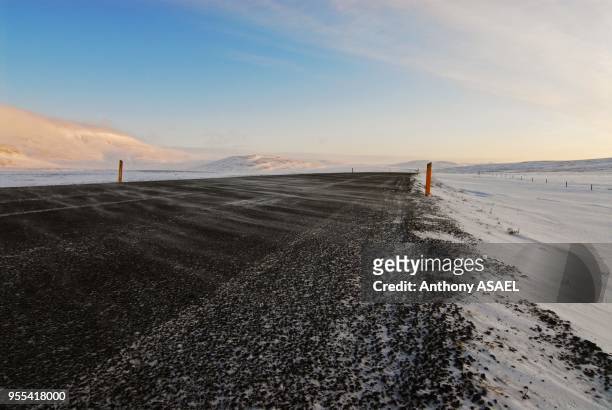 Macadam road in the middle of snow field, Inland, Iceland.
