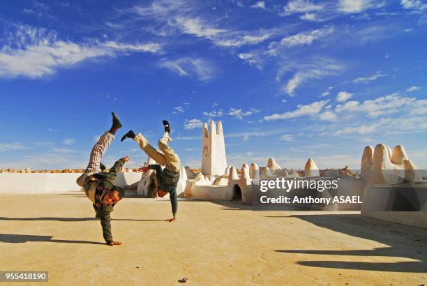 Two boys performing handstand against sky at the entrance of Melika's cemetery in background, Melika, Algeria.