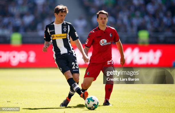 Jonas Hofmann of Moenchengladbach is challenged by Nicolas Hoefler of Freiburg during the Bundesliga match between Borussia Moenchengladbach and...