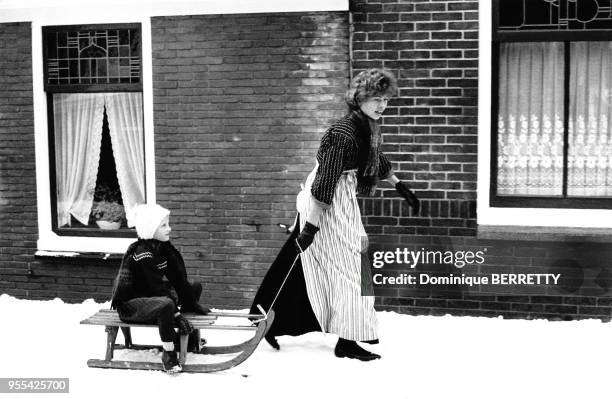 Femme tirant son enfant sur une luge dans une rue enneigée de Volendam, Pays-Bas.