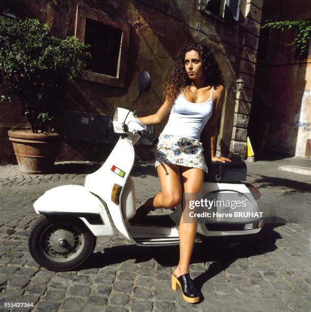 Jeune femme posant sur un scooter à Rome, Italie.