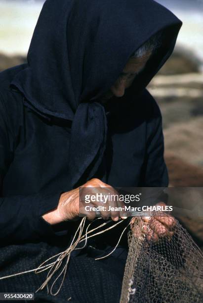 Femme âgée réparant un filet de pêche à Peniche, Portugal.