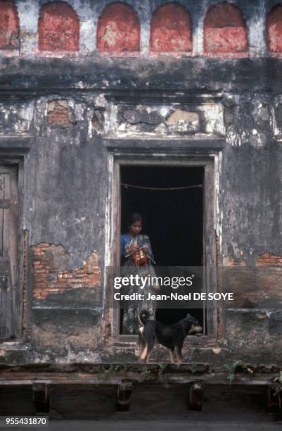 Jeune femme tricottant à la porte de sa maison à Calcutta, Inde.