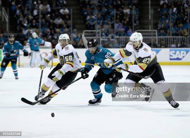 Mikkel Boedker of the San Jose Sharks goes for the puck against Erik Haula and Shea Theodore of the Vegas Golden Knights during Game Four of the...