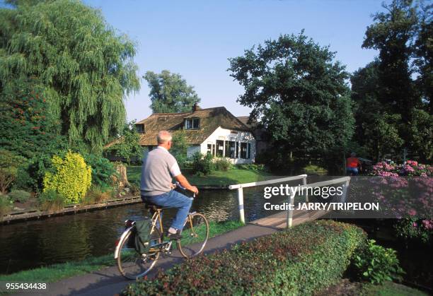 Cycliste au bord d'un canal du village lacustre de Giethoorn, Pays-Bas.
