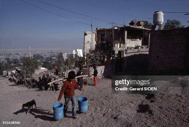 Enfant ramenant de l'eau dans le bidonville de Nezahualcoyotl, Mexique.