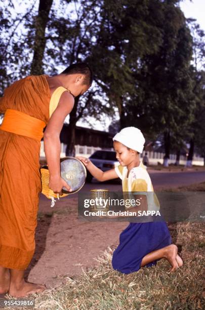 Moine bouddhiste récoltant des donts à Paksé, Laos.