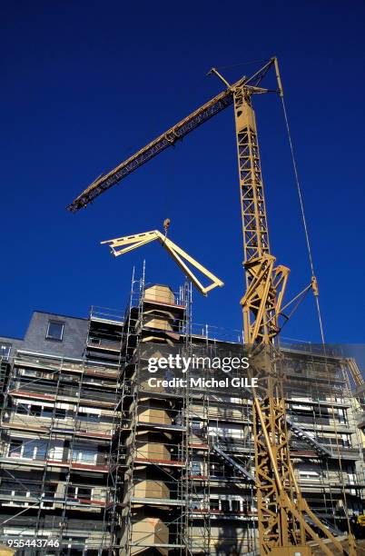 Chantier de construction de logements, Grue montant en haut de l' immeuble des éléments de charpente, Le Mans, Sarthe, France.