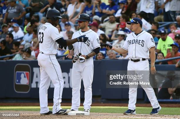 Franchy Cordero of the San Diego Padres is greeted by first base coach Skip Schumaker after hitting a RBI single in the seventh inning the during the...
