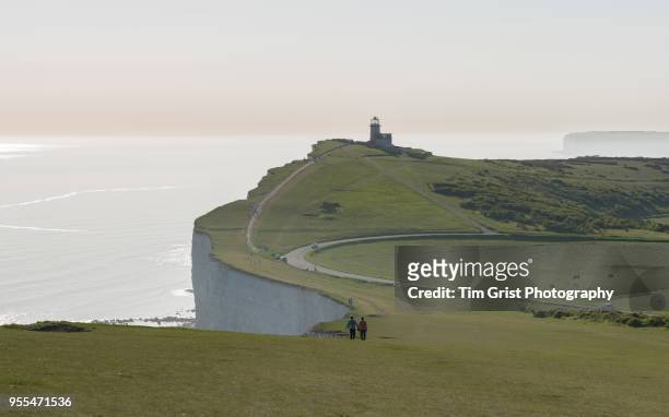 a couple walking towards belle tout lighthouse with misty background - belle tout lighthouse stock-fotos und bilder