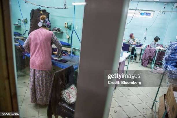 Worker irons clothing, left, as her colleagues operates sewing machines at an Alinex garment factory in Bishkek, Kyrgyzstan, on Wednesday, April 18,...