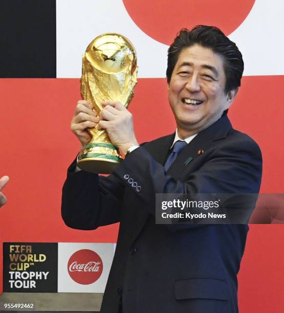 Japanese Prime Minister Shinzo Abe poses with the FIFA World Cup trophy at his office in Tokyo on April 27, 2018. The trophy arrived in Tokyo as part...
