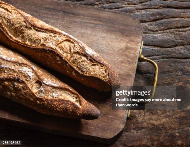 two baguettes over a wood board on an old piece of wood. still life. - french bread stock pictures, royalty-free photos & images