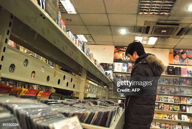 Chinese customer selects various pirated DVD movies at a shop in Beijing on January 2, 2010. While China has talked up its recent progress in...