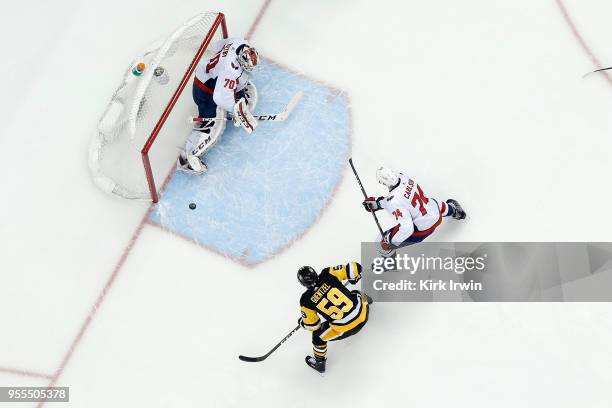 Braden Holtby of the Washington Capitals makes a save as Jake Guentzel of the Pittsburgh Penguins looks to gain control of the rebound in Game Four...