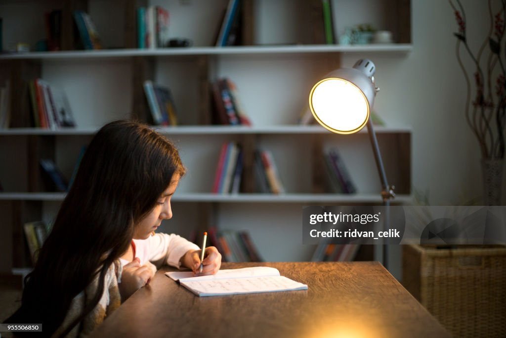 Kinderhand mit Bleistift zu üben auf ein Buch zu schreiben.