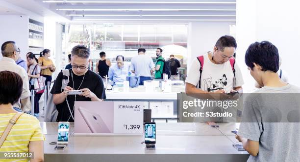 Customers look at smartphones displayed, inside of the Xiaomi Corp. Store on Nathan Road in Hong Kong on May 7, 2018 in Hong Kong, Hong Kong. A...