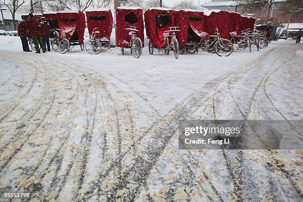 The tricycle carters stand near their tricycles on the snow-covered street on January 3, 2010 in Beijing, China. Authorities in Beijing and Tianjin...