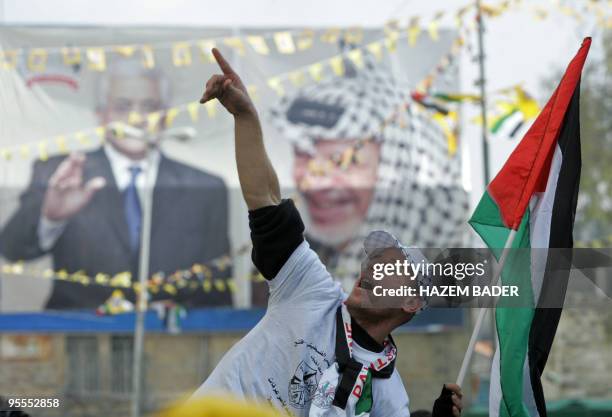 Fatah supporter waves a national flag in front of a billboard bearing pictures of late Palestinian leader Yasser Arafat and his successor, current...